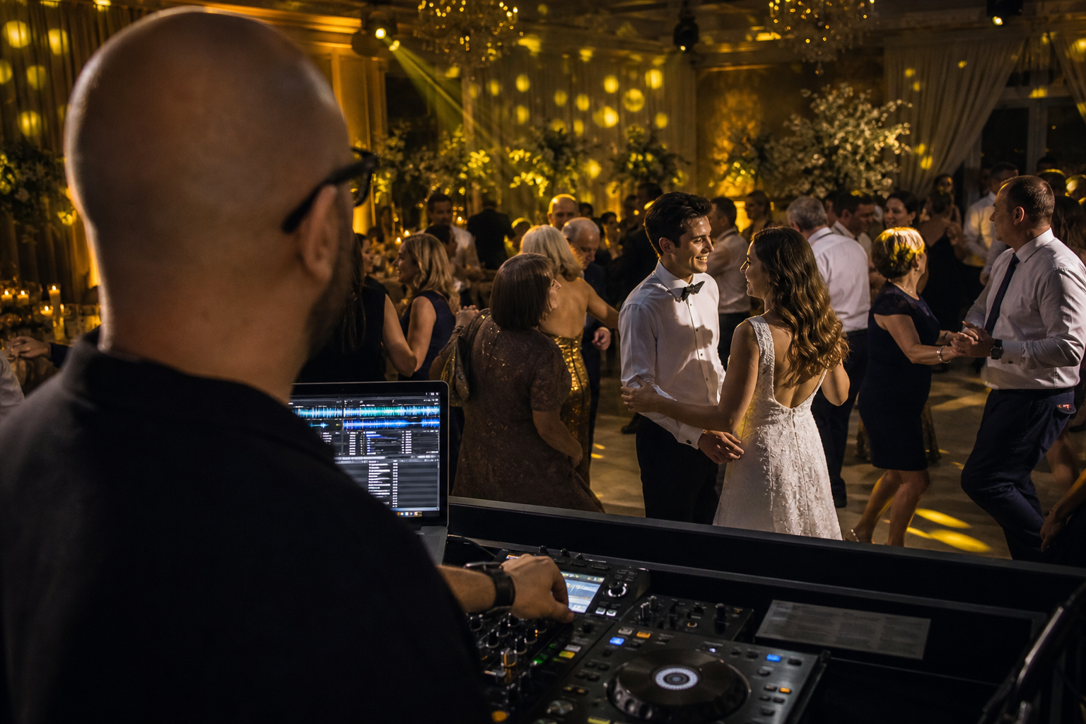 DJ urmărește invitați din mai multe generații care dansează împreună la nuntă.